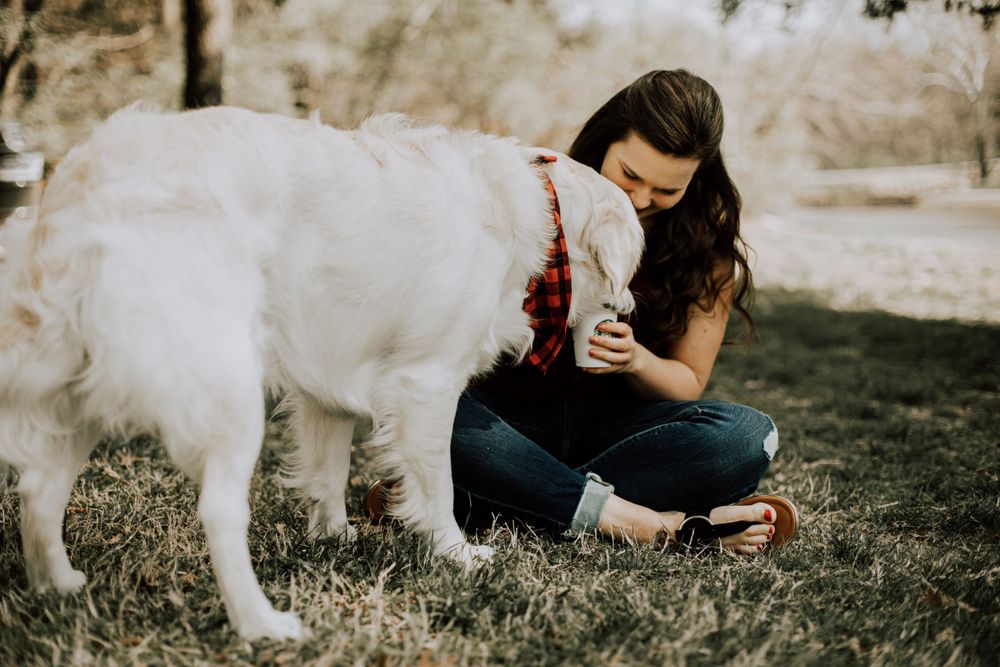 A sweet moment shared between a white dog and companion while enjoying treats outdoors.