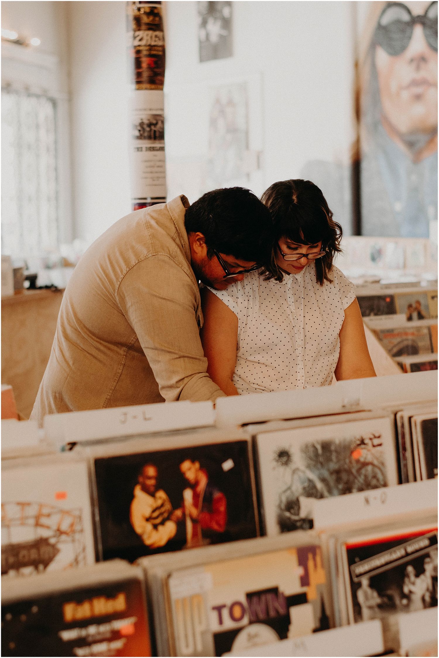 Couple sharing intimate moment while browsing vinyl records at music store.