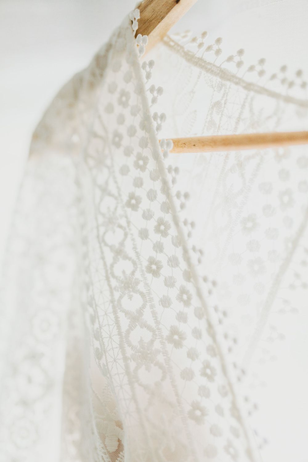 Close-up of delicate white lace pattern on wedding dress fabric.
