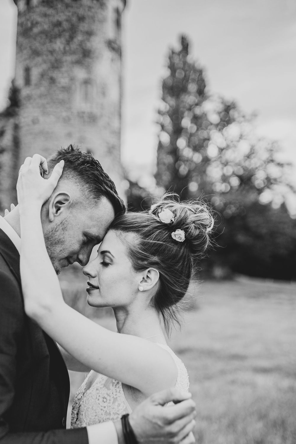 An intimate black and white wedding portrait captured near a stone tower.