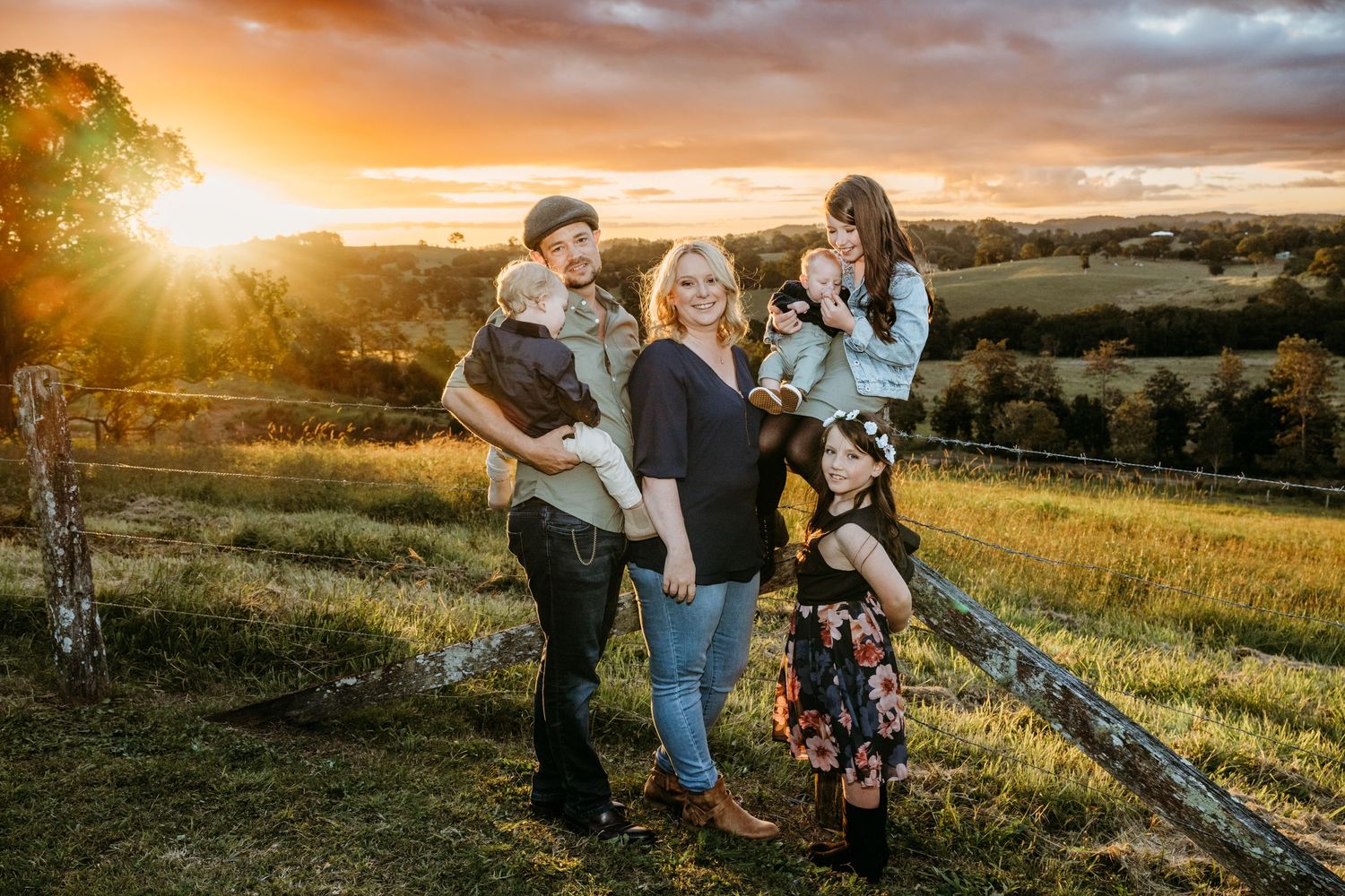 Small group posed together in field during golden sunset with rolling hills behind them.