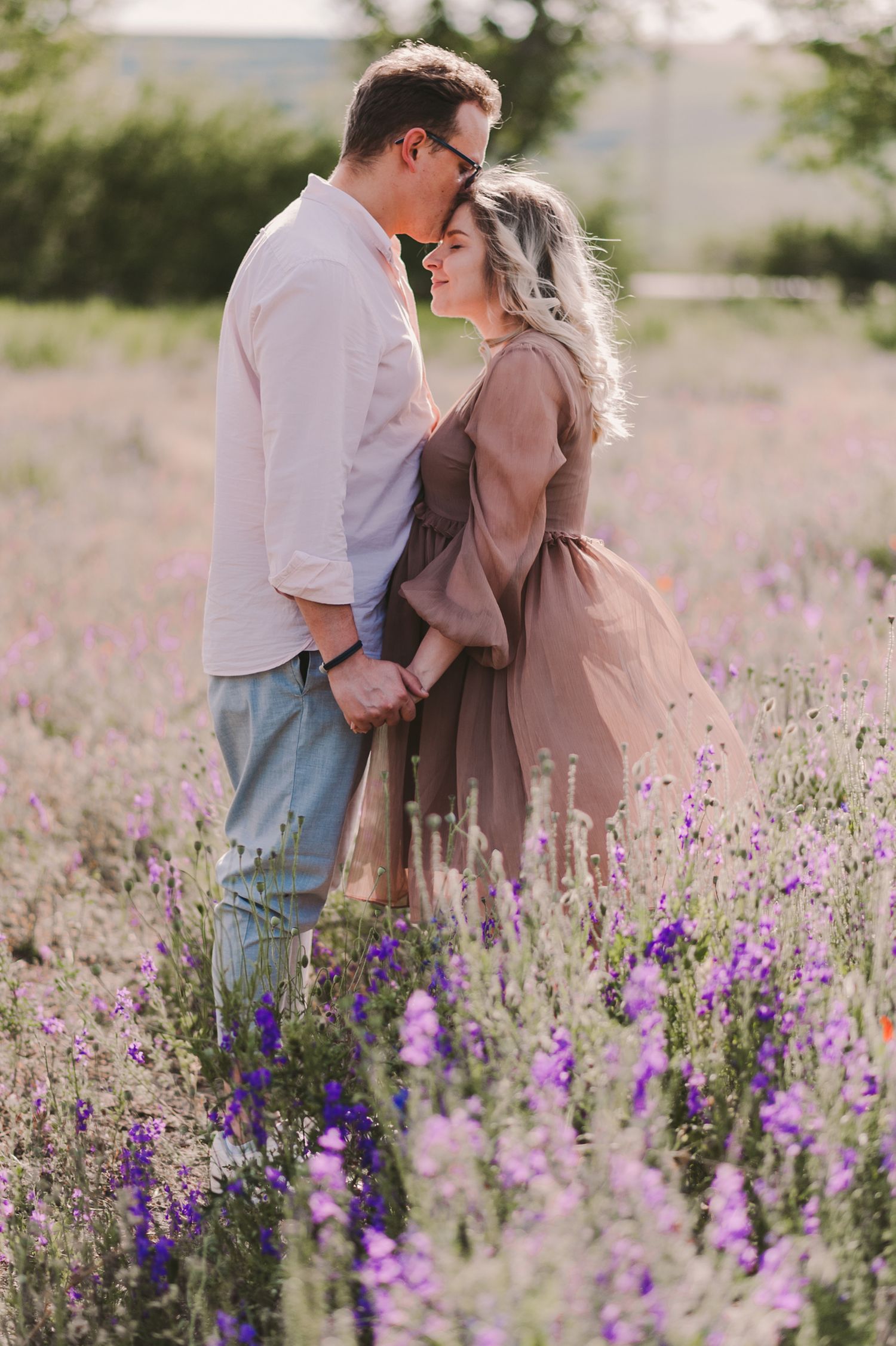A romantic photoshoot in a field of purple lupines during golden hour lighting.