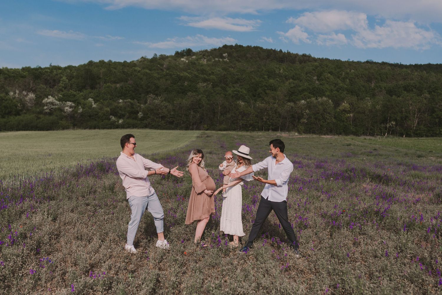 Group of people walking together through a purple wildflower field on a sunny day.