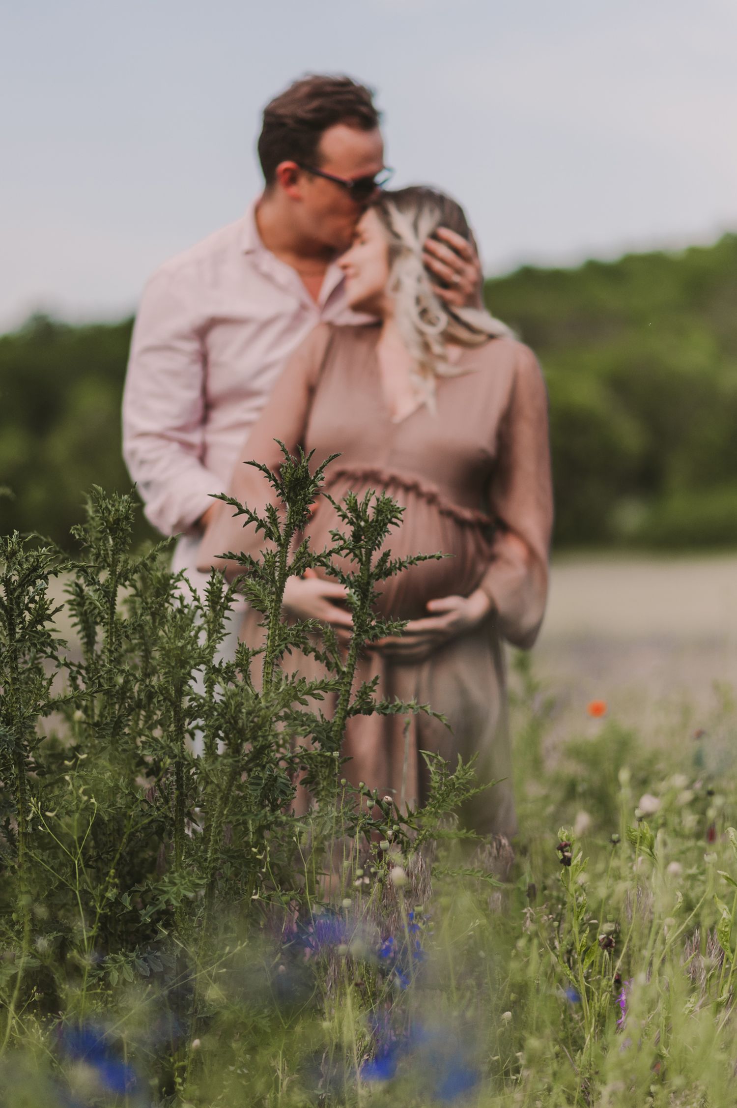 A romantic photoshoot in a meadow with vibrant blue wildflowers and natural greenery.