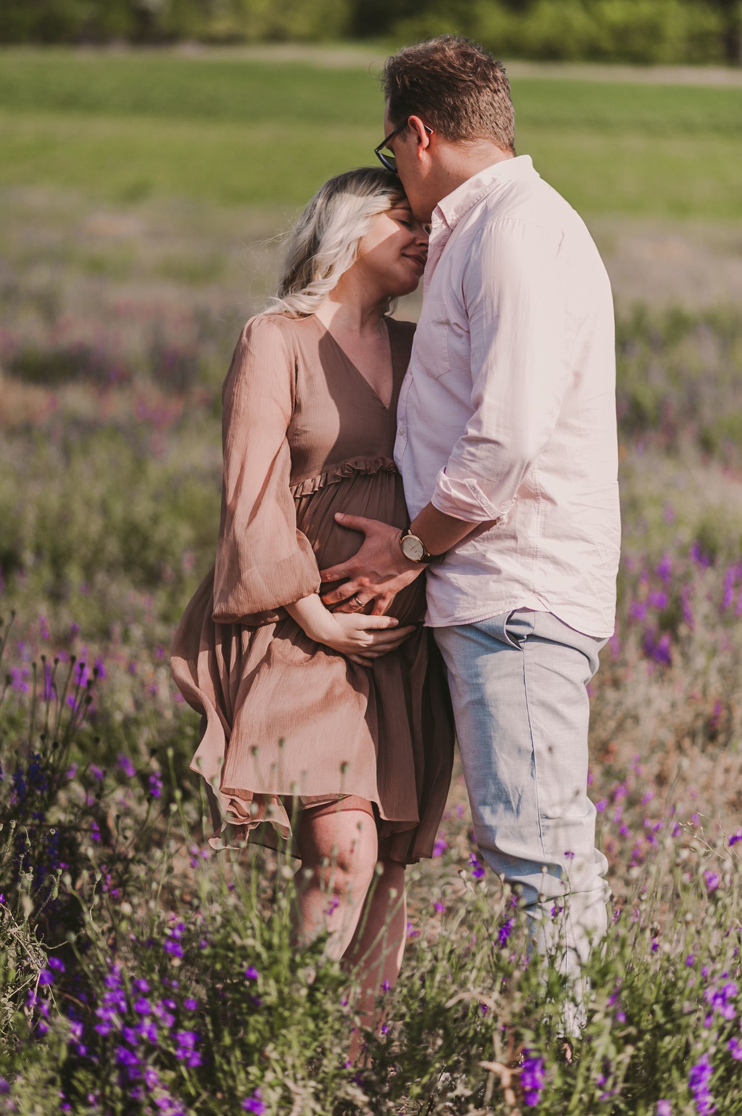 A couple shares tender moments in a field of purple lupines during golden hour.