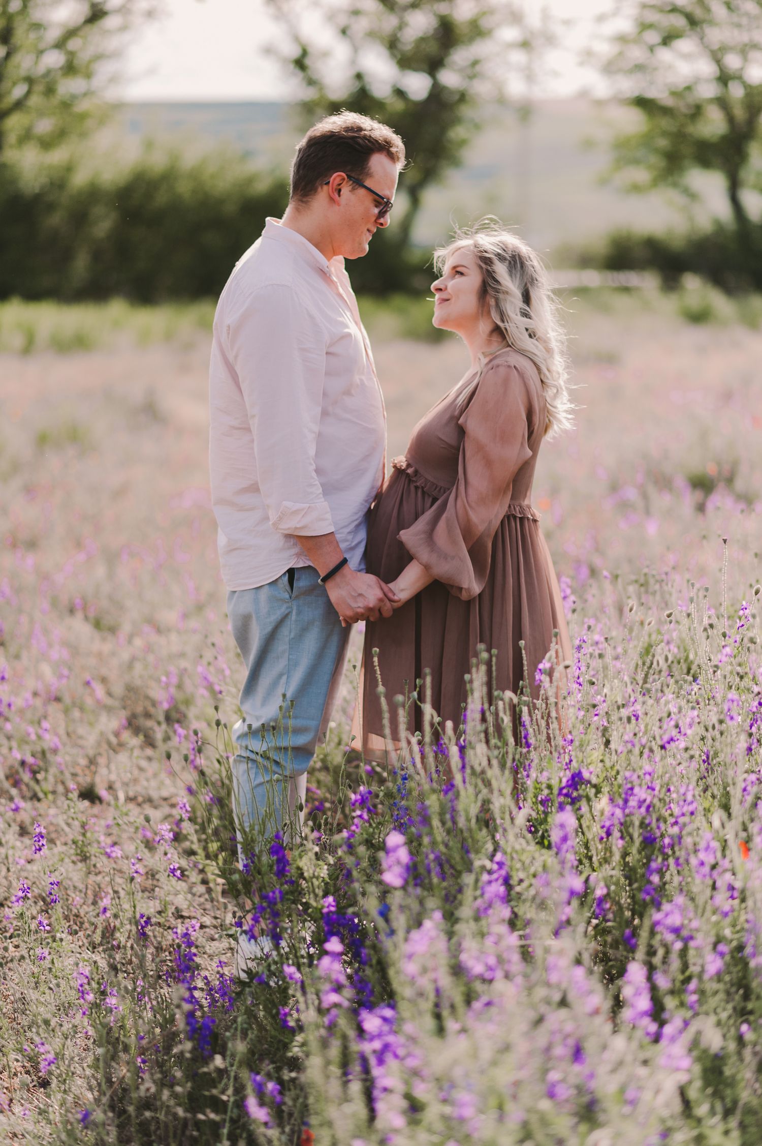 A couple shares intimate moments among blooming purple wildflowers in a spring meadow.
