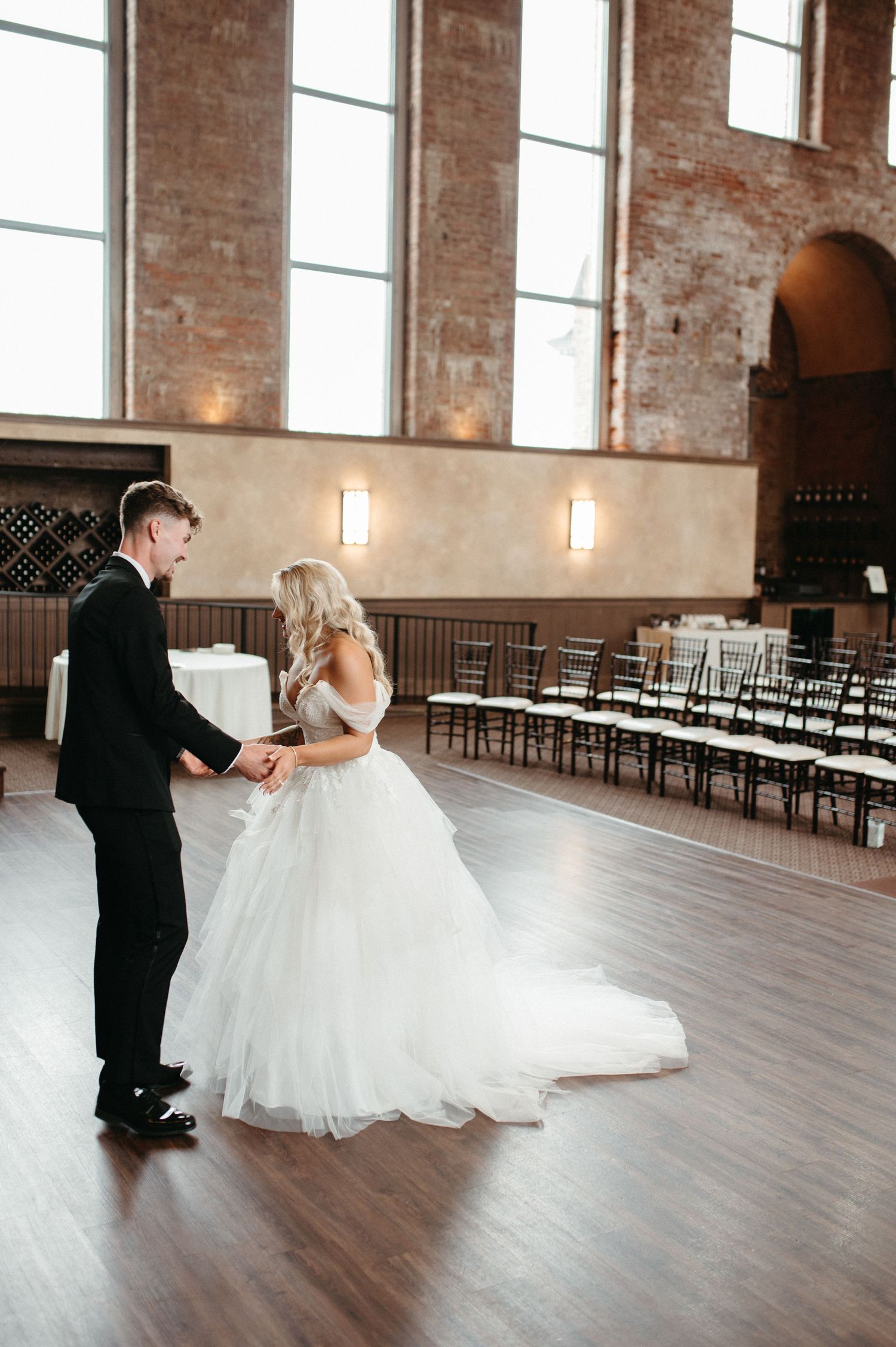First look between couple in an elegant venue with tall windows and wooden floors.