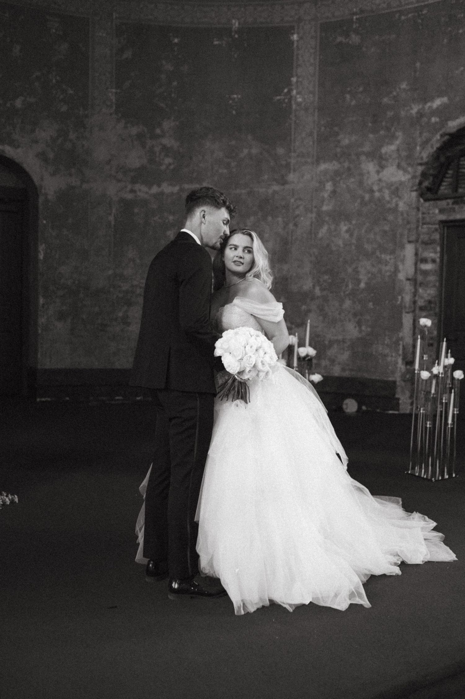 Black and white wedding portrait capturing intimate moment between newlyweds in historic venue.