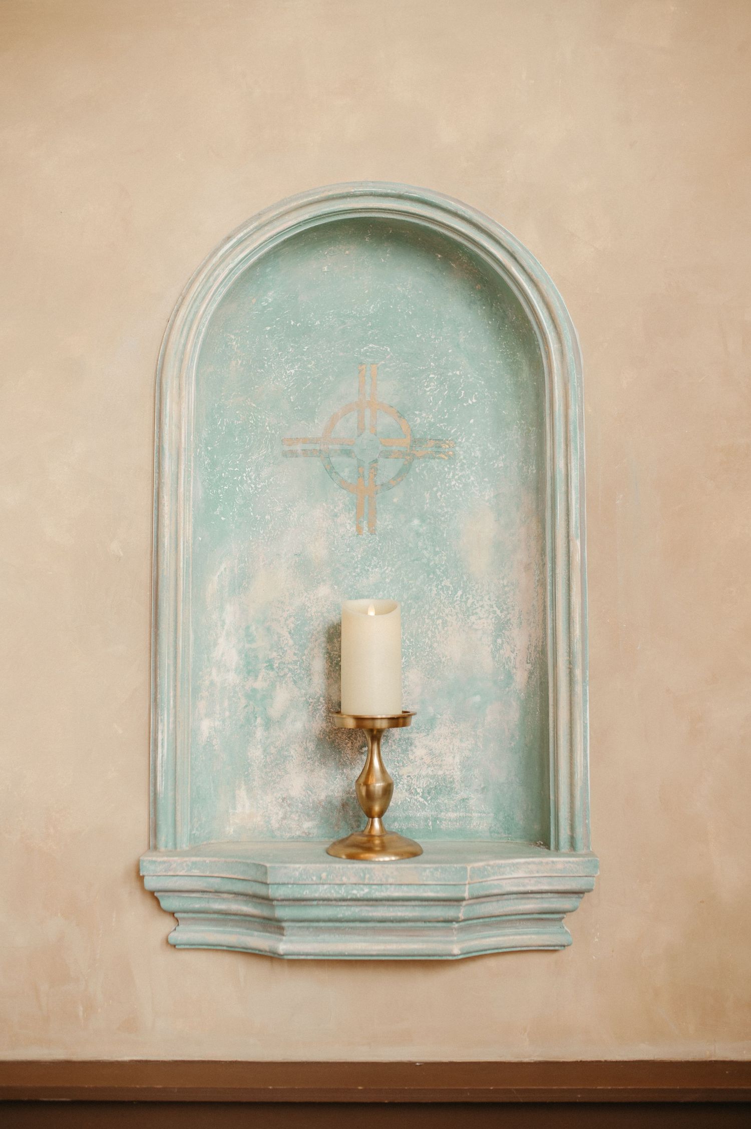 A vintage mint green wall alcove with a single white candle in a brass holder creating a romantic atmosphere.