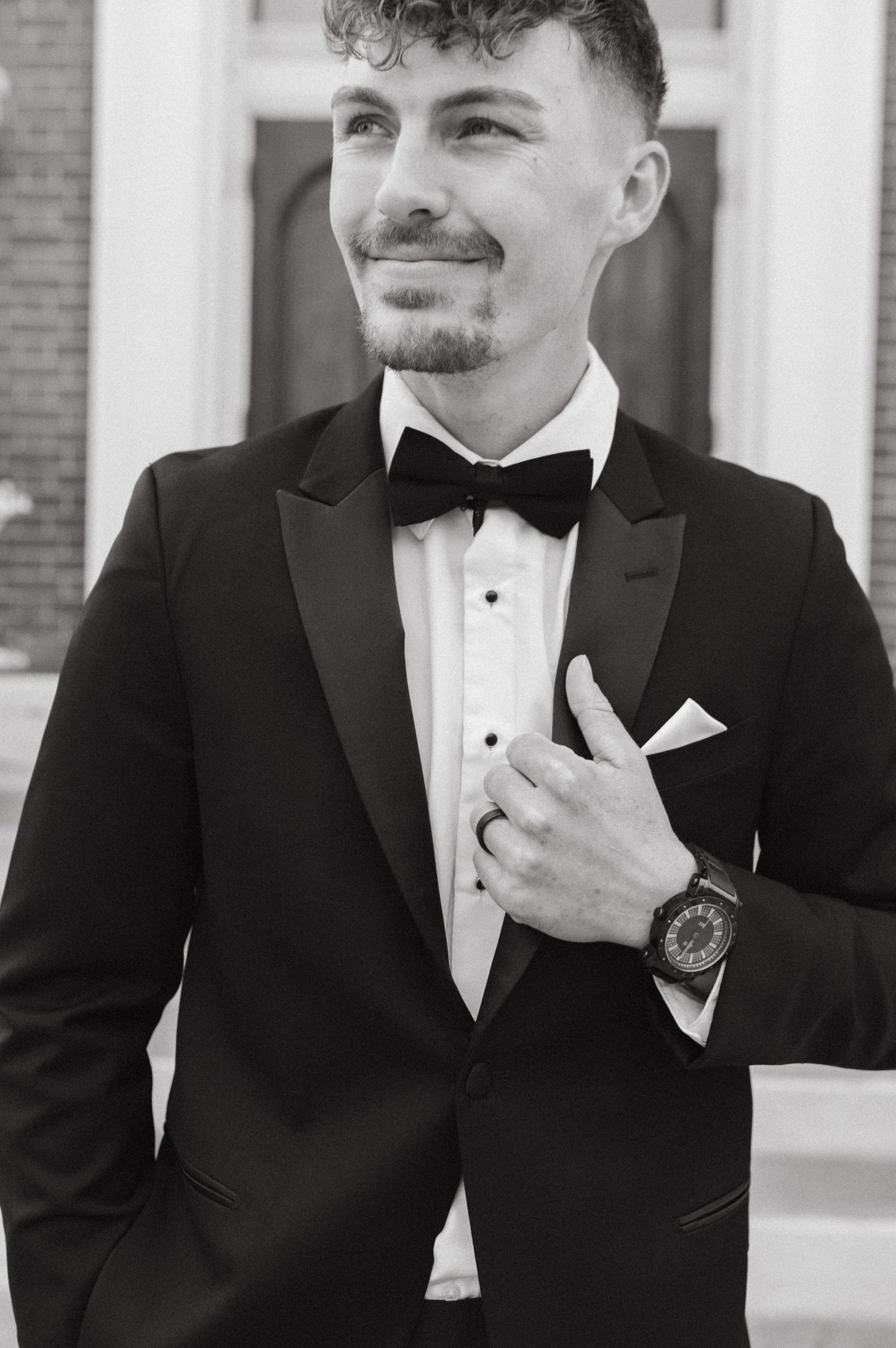 Close-up of groom in formal black tuxedo with bow tie and watch.