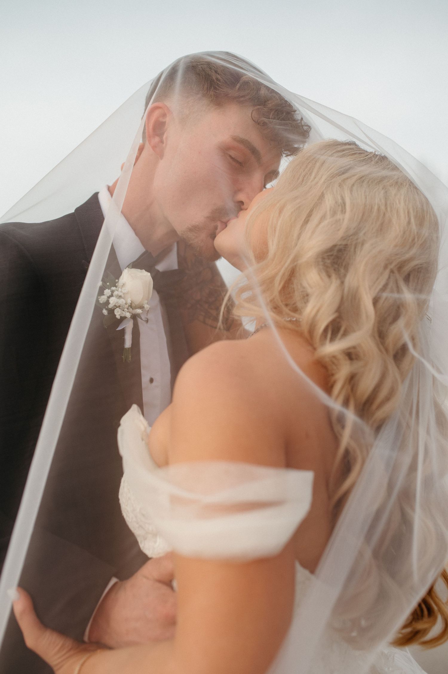 An intimate moment under a wedding veil with soft dreamy lighting.