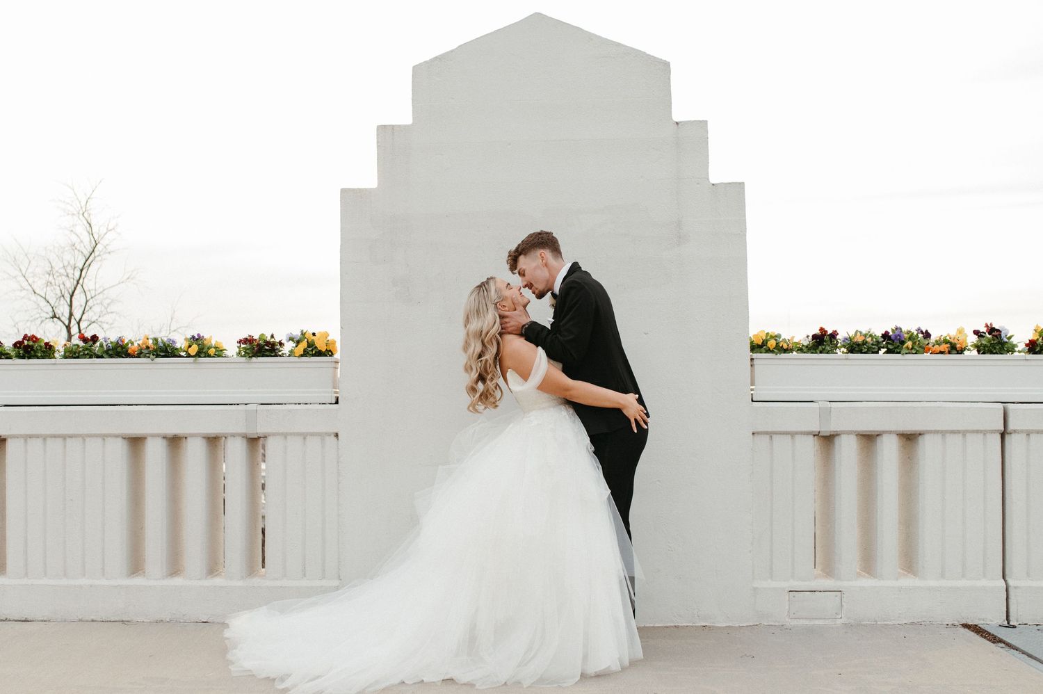 A tender wedding moment captured against a stepped white architectural wall.