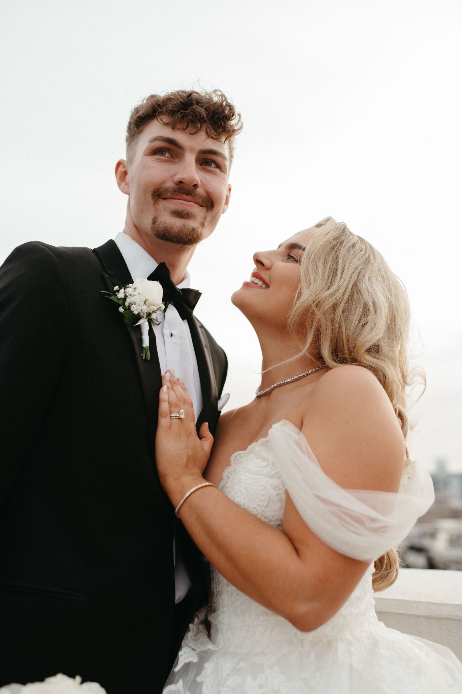 An intimate wedding portrait captured against an outdoor backdrop with natural lighting.