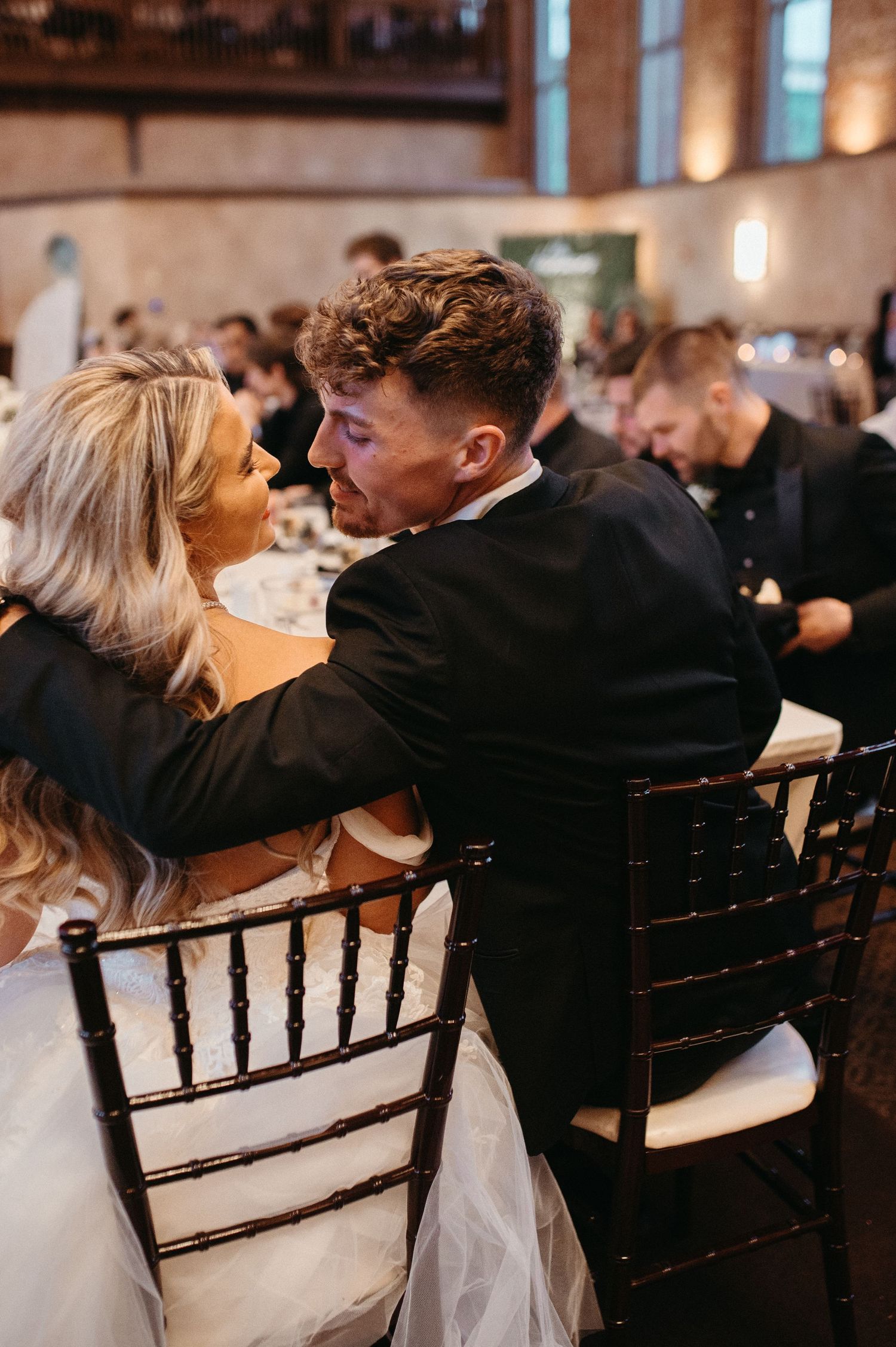 An intimate reception moment captured at wedding dinner with dark wood Chiavari chairs.