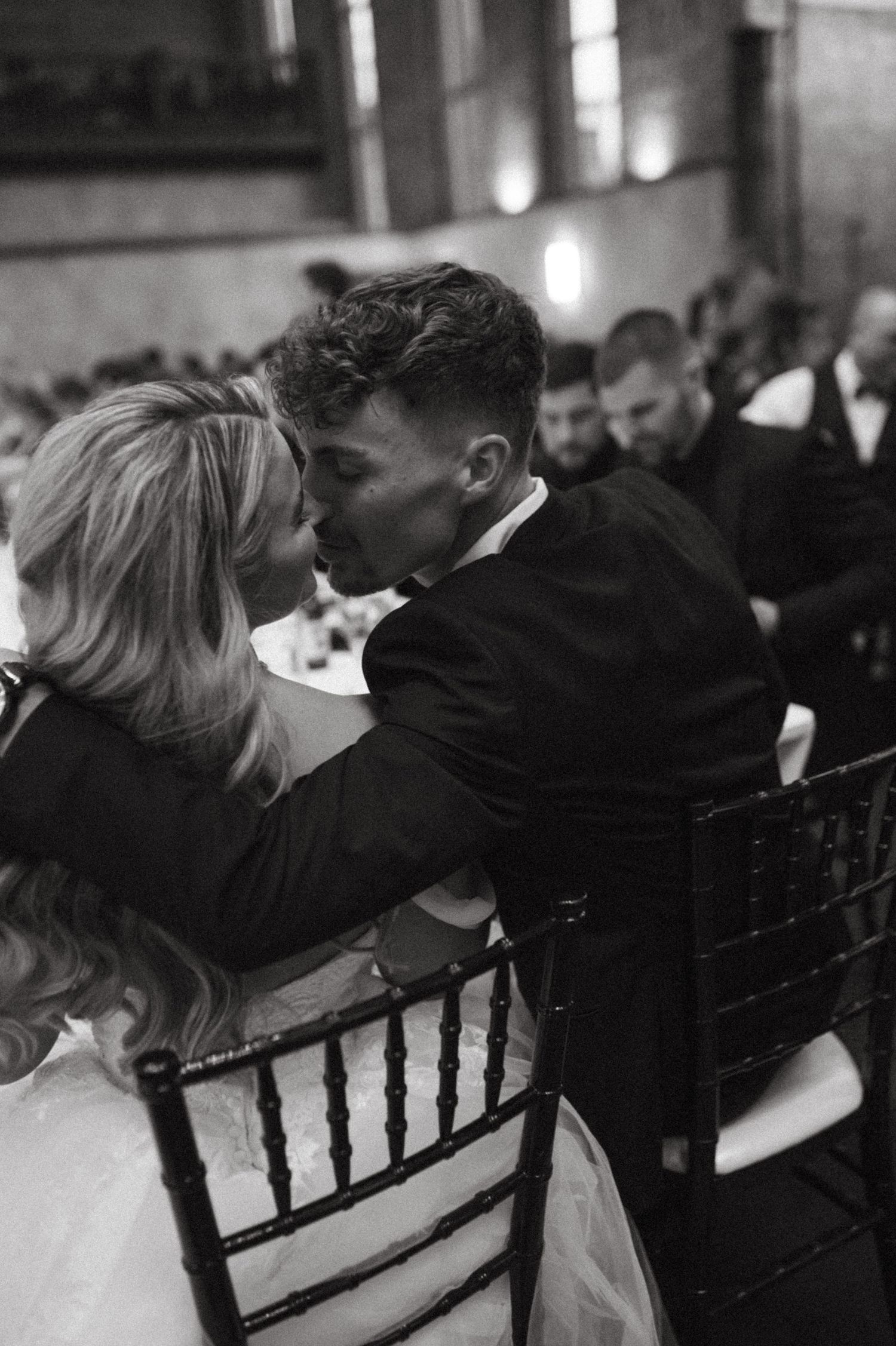 Black and white photo of newlyweds sharing an affectionate moment during their wedding reception.