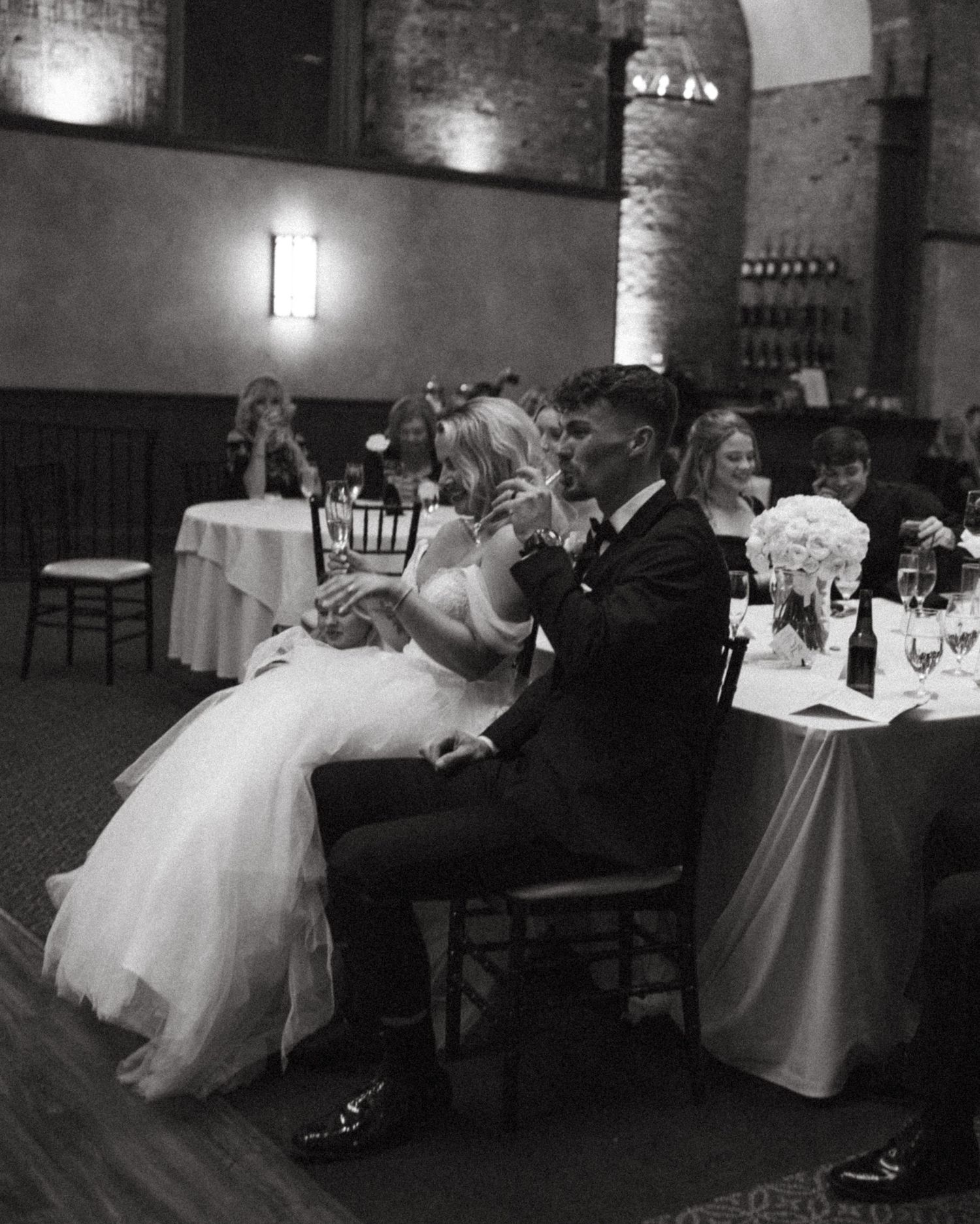 Black and white photo of couple sharing intimate moment at wedding reception in brick venue.