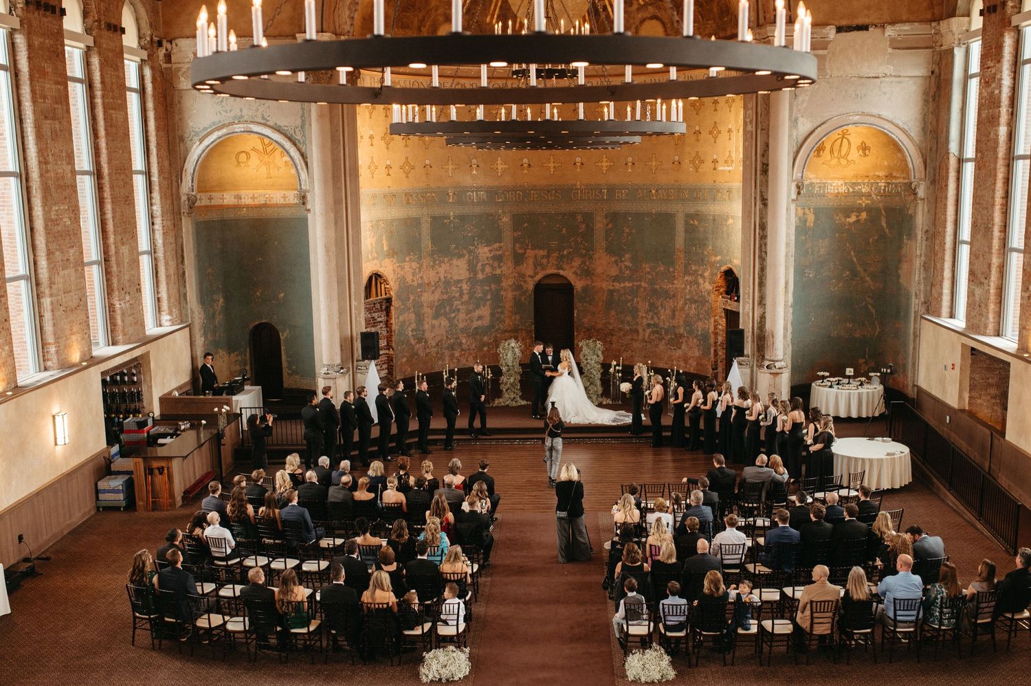 An aerial view of an elegant church wedding ceremony with guests seated in a grand historic venue.