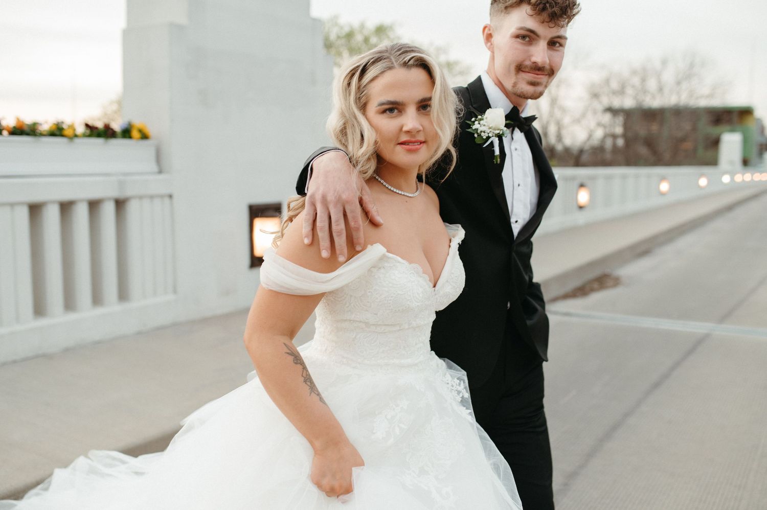 A sunny wedding portrait showing the couple walking together on a white columned terrace.
