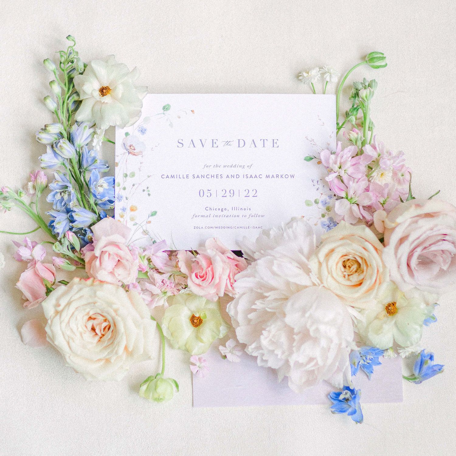 Save the date card surrounded by delicate pink and blue flowers on white background.