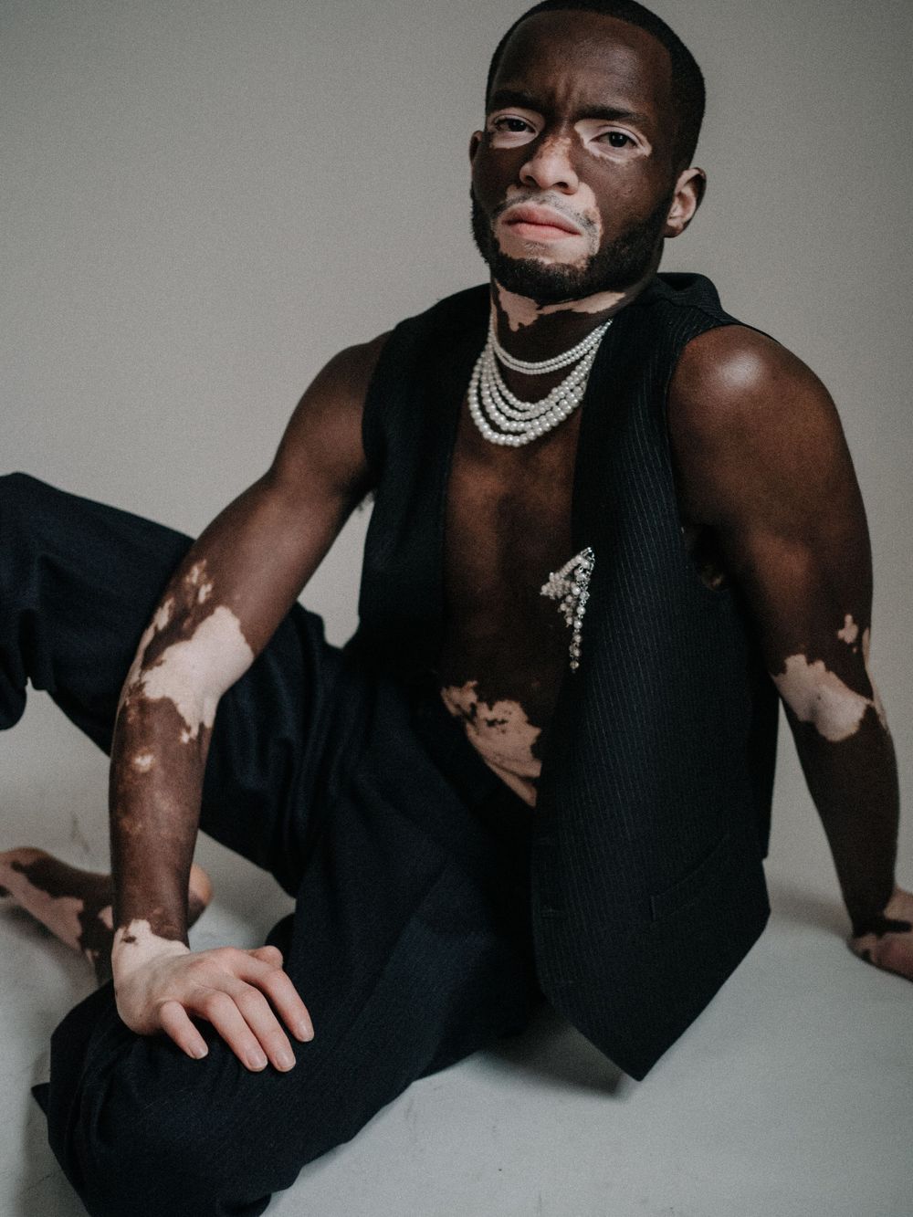 Artistic portrait showcasing unique skin tones and layered silver necklaces against dark attire.
