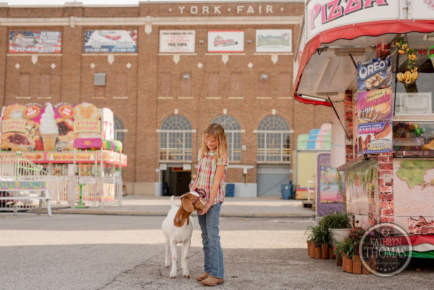 Show dog and handler posing in front of York Fair building with carnival decorations.