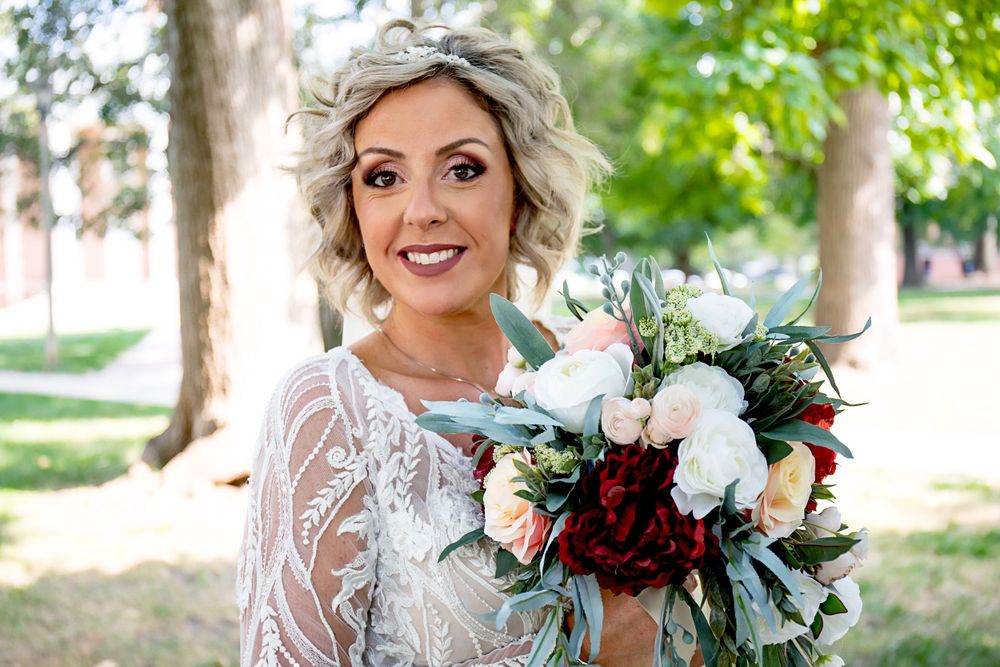 Bride holding stunning burgundy and white bouquet with eucalyptus in outdoor garden setting.
