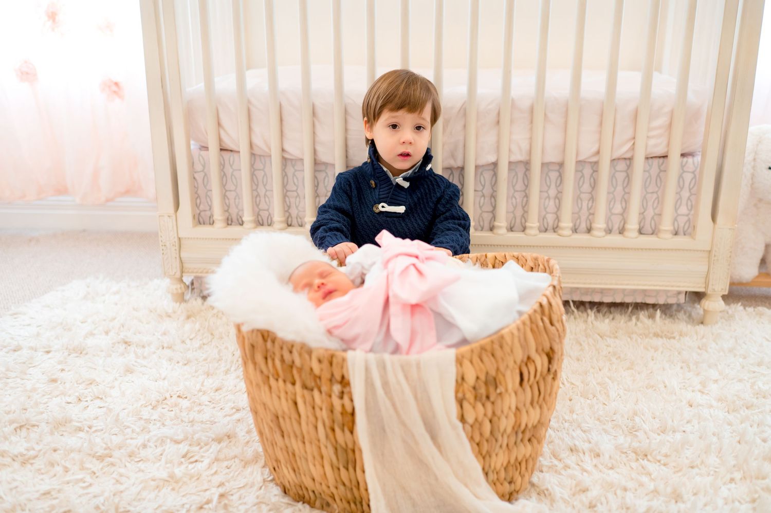brother wearing a blue sweater taking in home newborn lifestyle photography for his baby sister