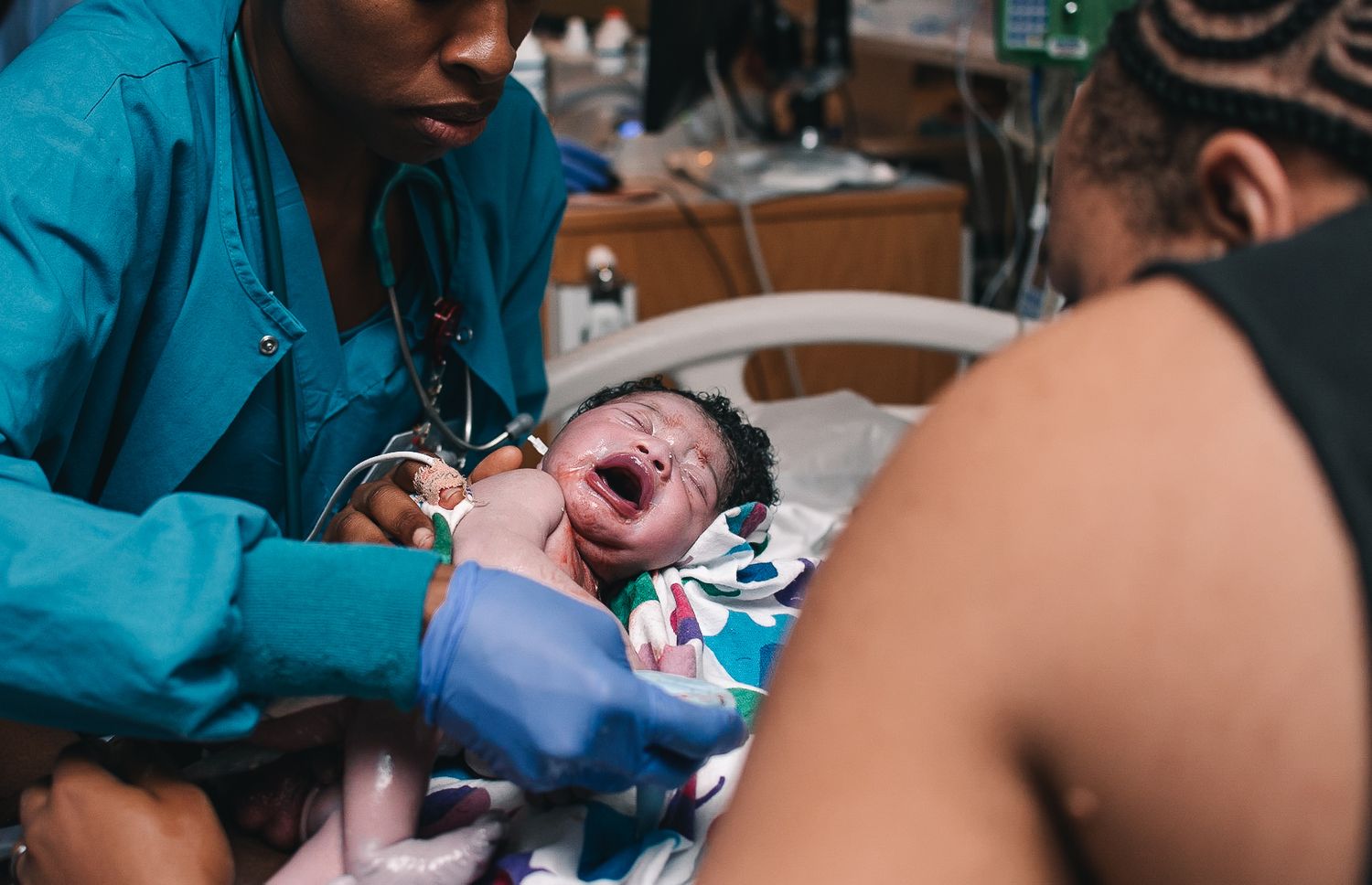 nurse placing crying baby on mother's chest after giving birth