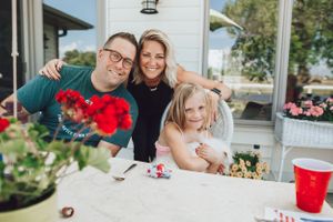 A happy family moment on a porch with colorful flowers in the foreground.