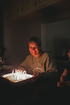 Birthday cake with glowing candles illuminates a dark room in a series of candlelit photos.