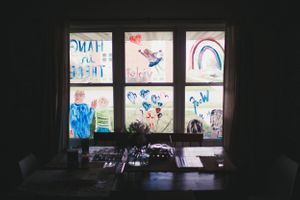 Children's artwork and drawings displayed in window panes against dark background.