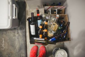 A cluttered garage shelf holds various tools, bottles, and household supplies.