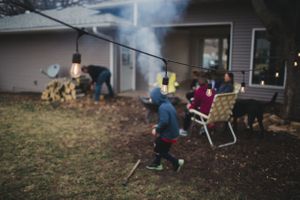 People gathered around a campfire in a backyard on a dark evening.