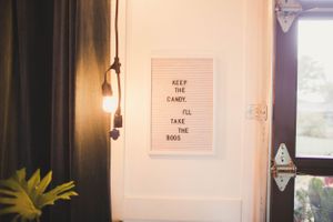 A minimalist white wall with framed text art and wall sconce lighting.
