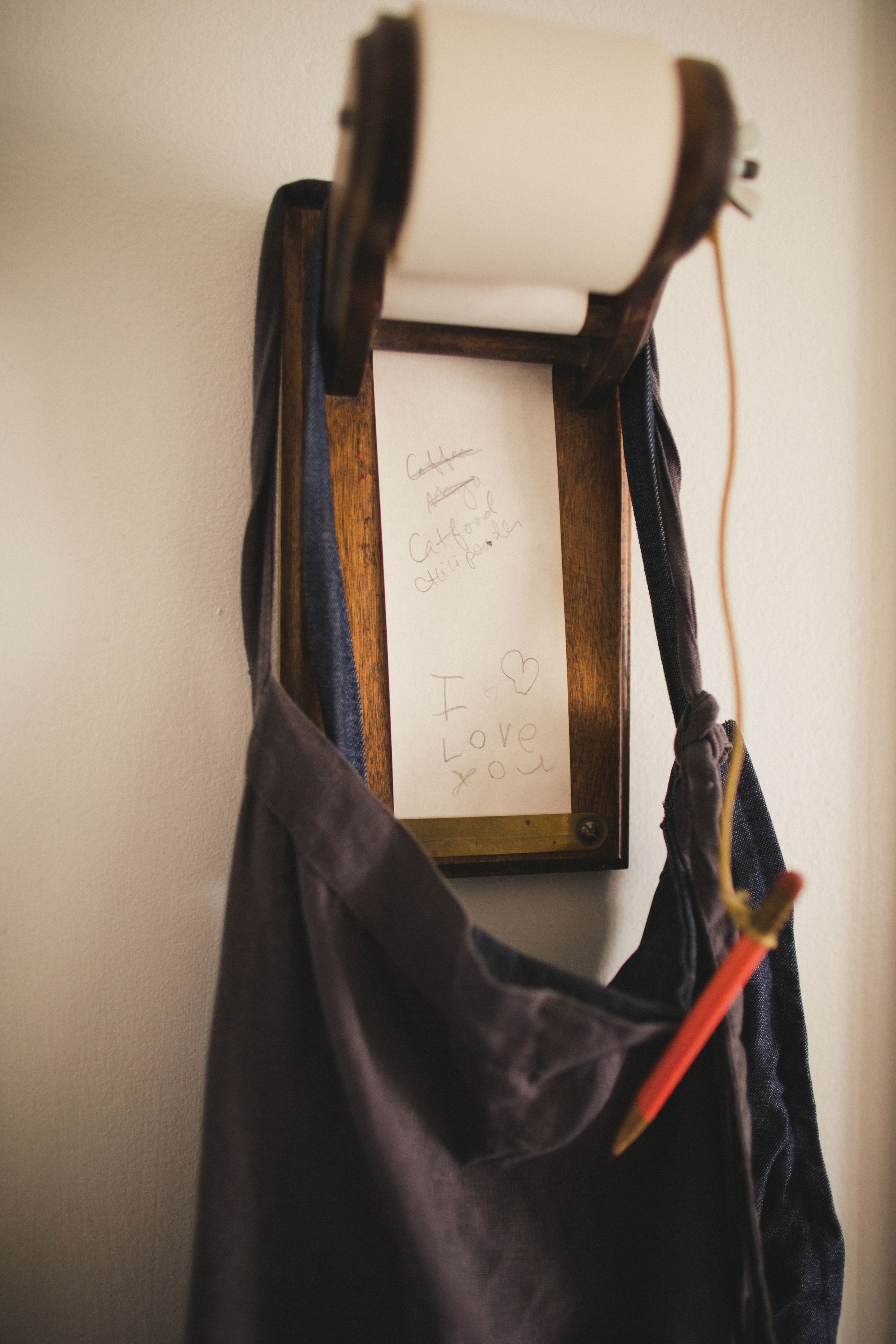 Dark clothing items hanging on hooks against a white wall with framed artwork.