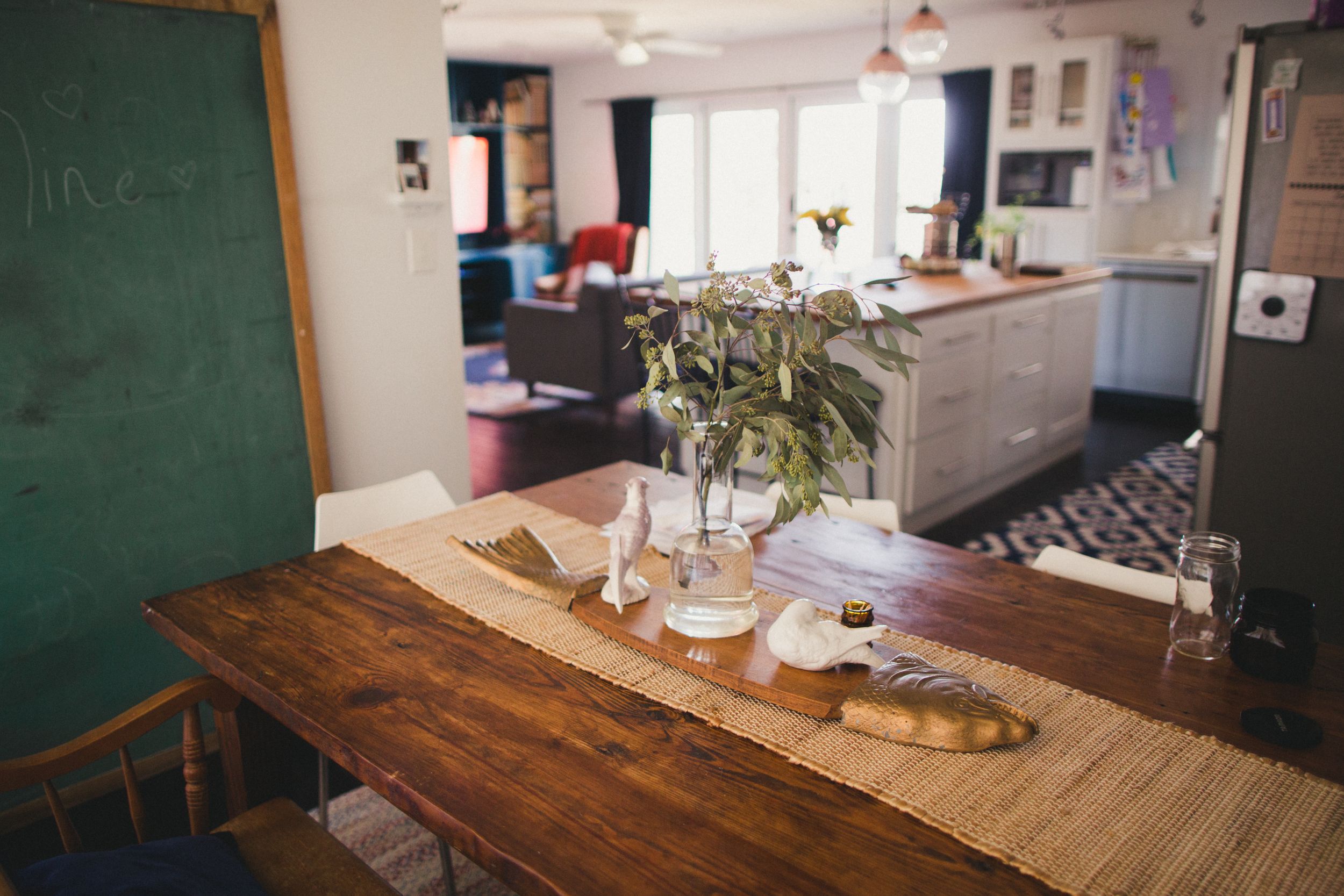 Rustic wooden table in a room with green chalkboard and natural lighting.