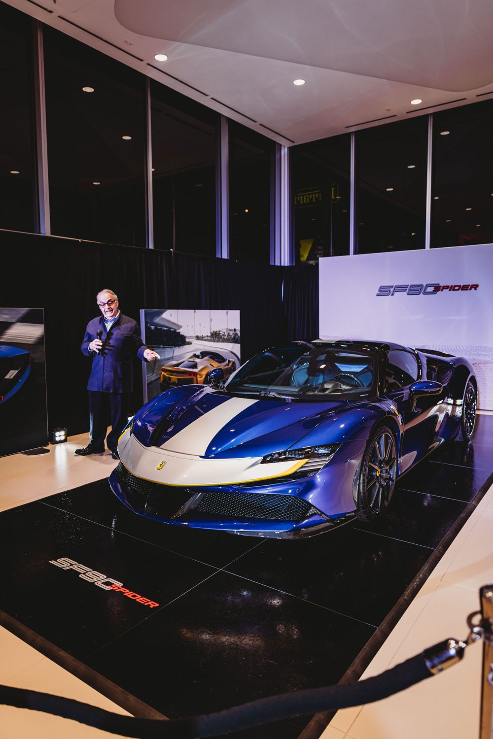 Sleek blue and silver supercars on display in a dark showroom with dramatic lighting.