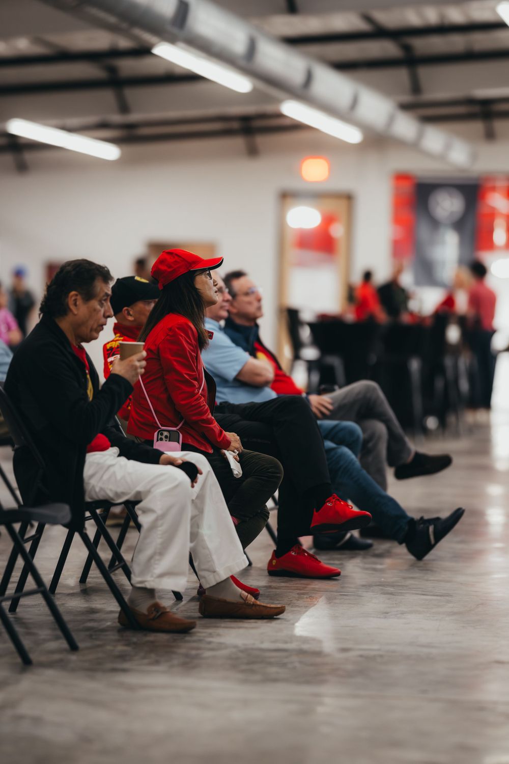 People seated in rows of folding chairs at an indoor event venue.