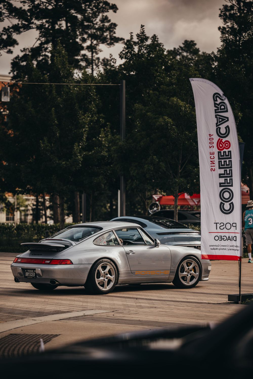 Classic vintage cars lined up at an outdoor car show with event banners in the background.