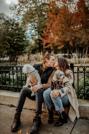 A couple shares a tender moment with their two dogs among fall foliage.