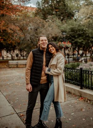 A couple shares a tender moment on an autumn day in the park wearing casual fall outfits.