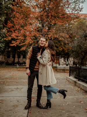 A romantic couple shares a playful moment on a fall day in the park.