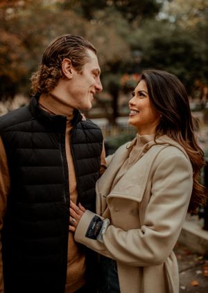 A couple shares an intimate moment while wearing fall clothing in a park setting.