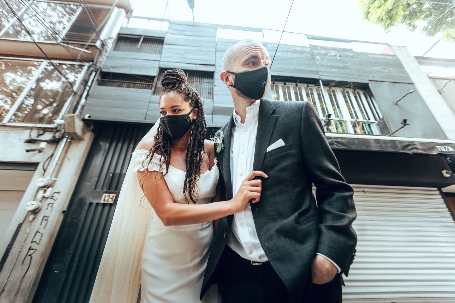 Modern wedding couple wearing protective face masks while walking together in an urban setting.