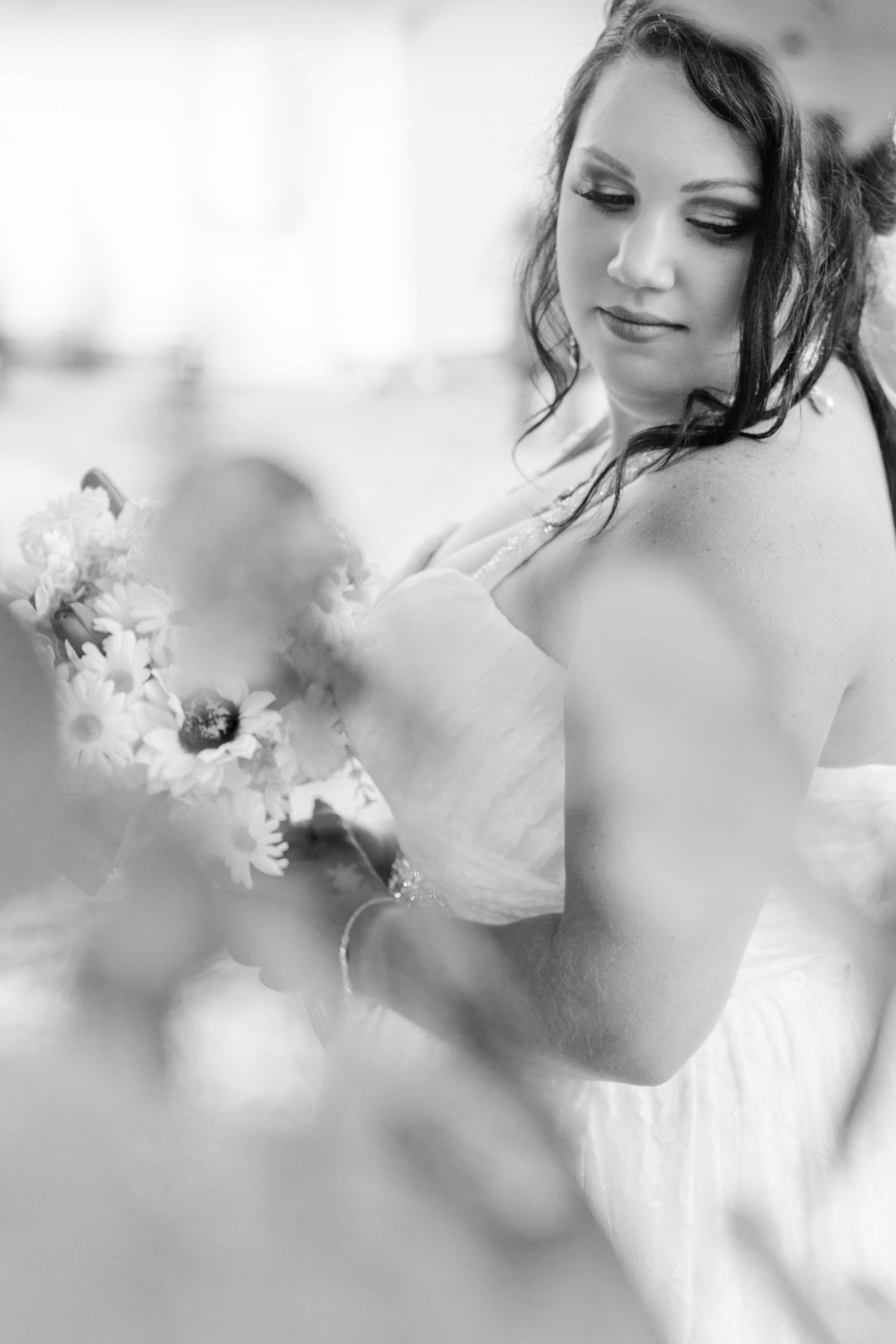 Artistic black and white bridal portrait through flowers.