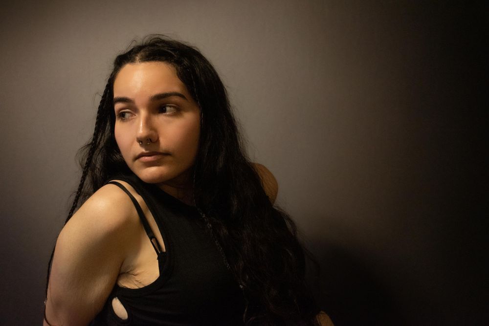Artistic portrait featuring dramatic side lighting on person with flowing dark hair.