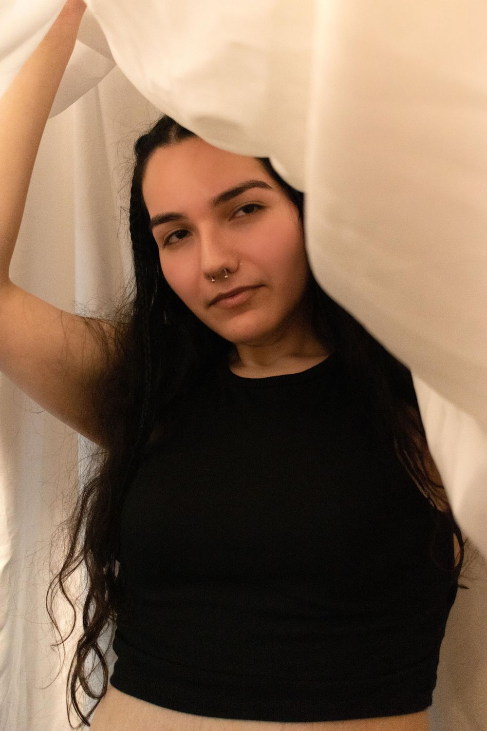 Creative portrait with white fabric framing person in black top with long dark hair.