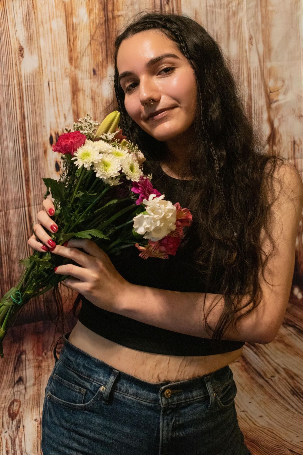 Portrait with mixed flower bouquet against wooden backdrop wearing casual attire.