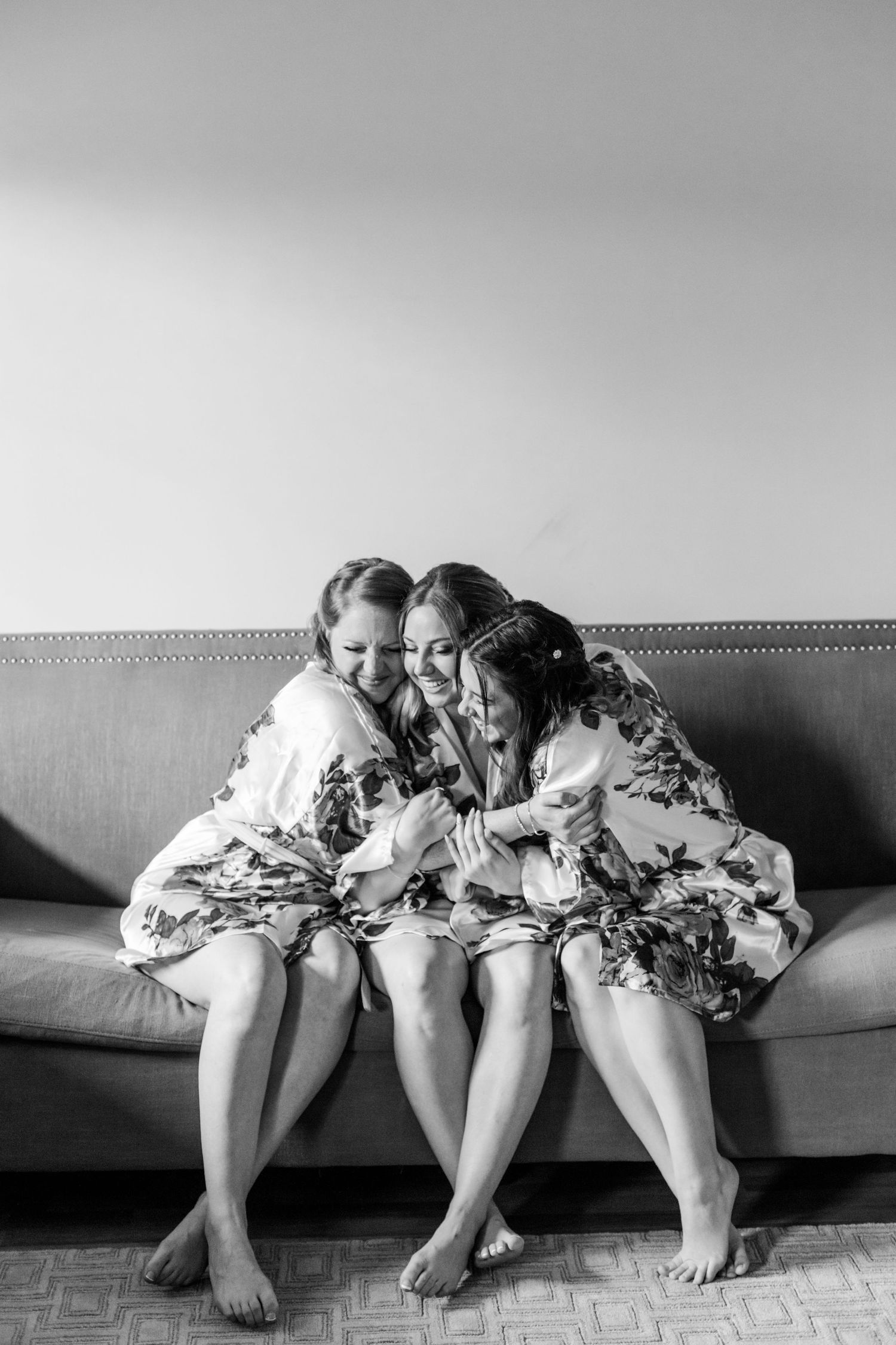 Black and white photo of three people in matching robes sitting together on a couch.