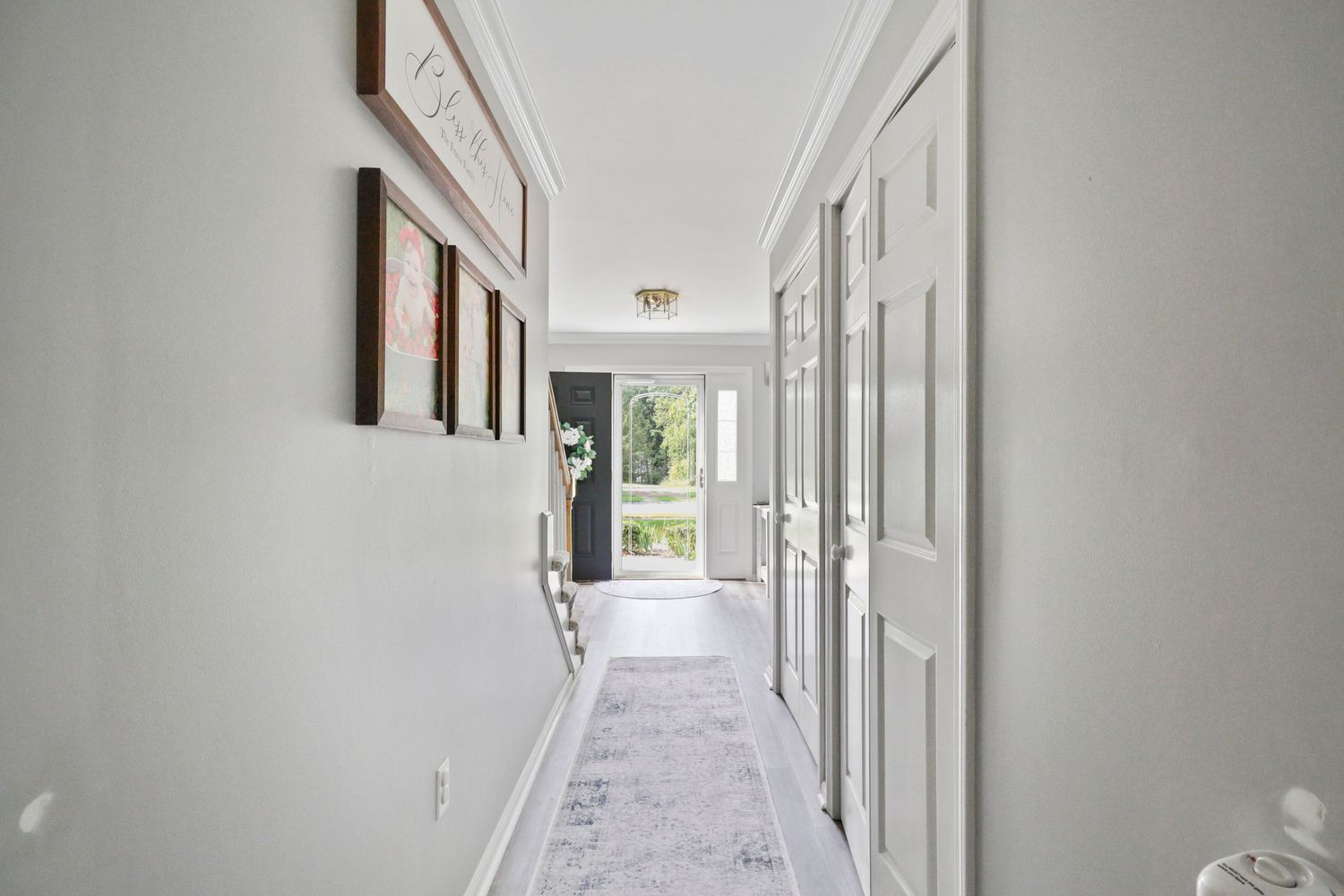 Long white hallway with recessed lighting and multiple doorways leading to different rooms.